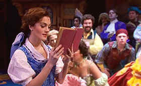 Belle quietly reads a book while townspeople sing around her.
