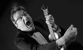 A man plays the ukulele while yelling.
